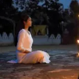 a woman sitting on the ground in front of a light