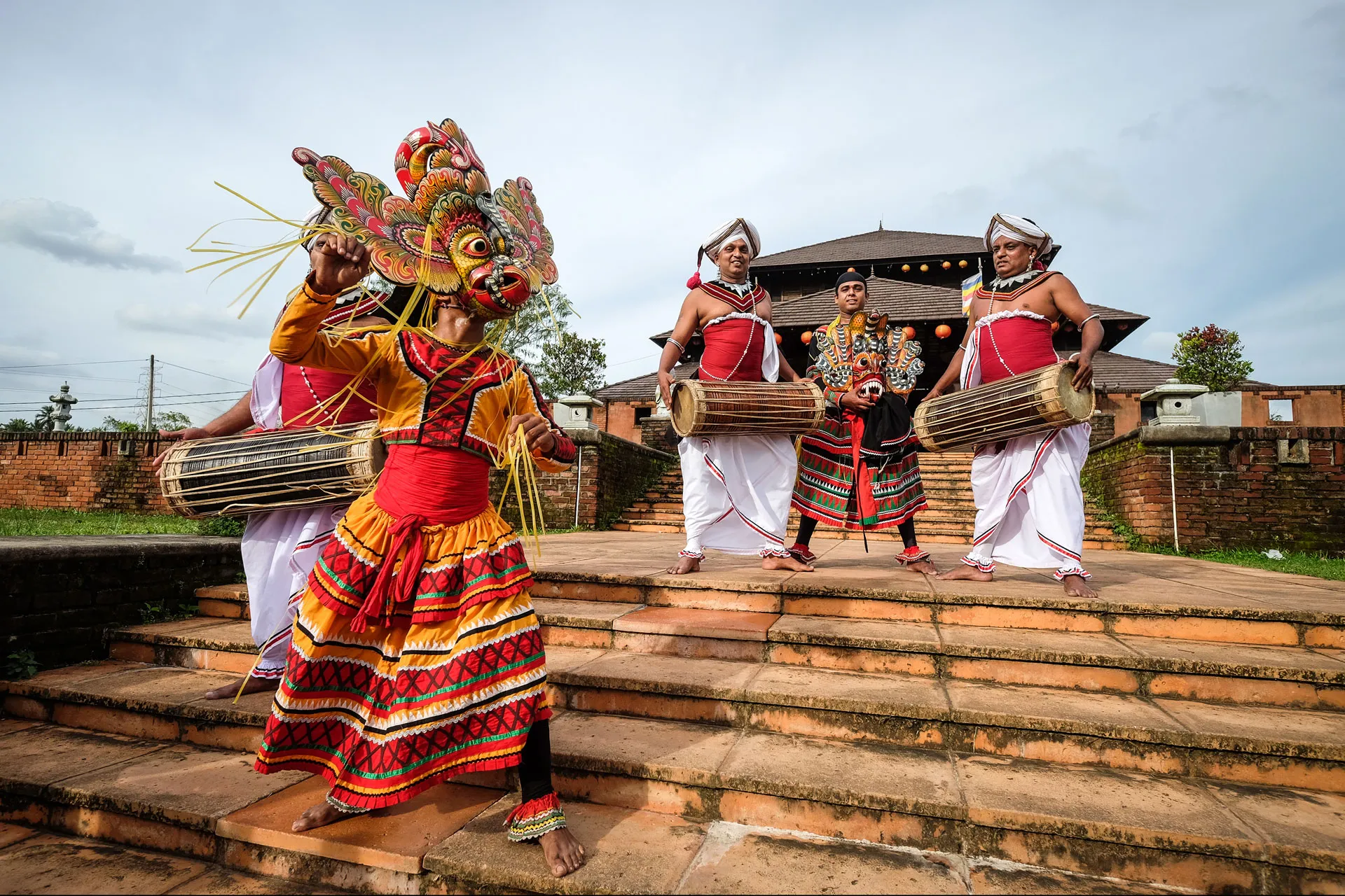 Traditional-Sri-Lankan-devil-dancer-wearing-a-mask-with-another-dancer-and-three-Sri-Lankan-traditional-drum-players
