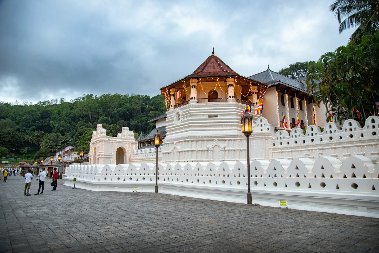 Photo by Chathura Anuradha Subasinghe a white building with a gold roof with Temple of the Tooth in the background