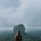 woman in red shirt standing on mountain top