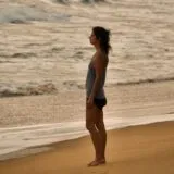 a woman standing on a beach next to the ocean